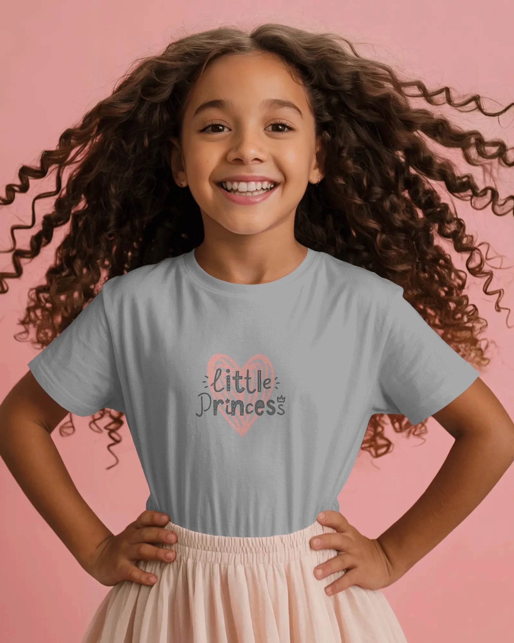 Young girl wearing a gray t-shirt with a unicorn design on a pink background