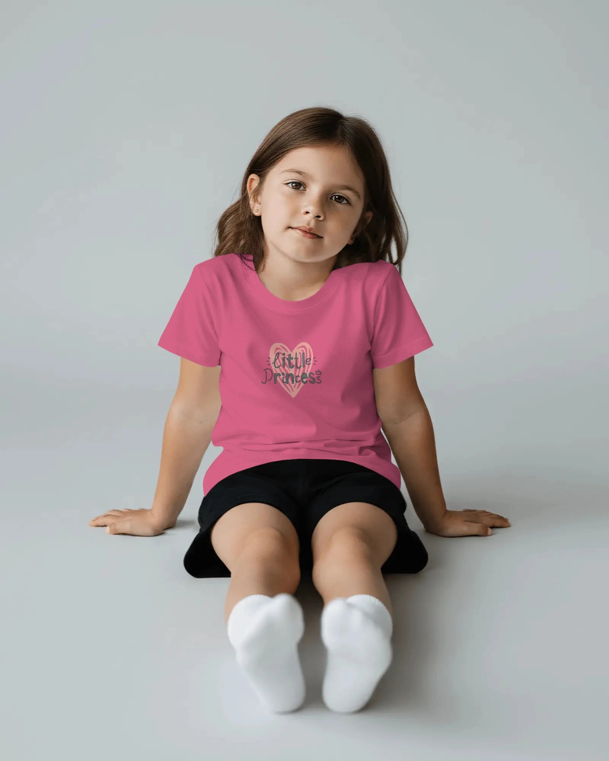 Young girl wearing a pink t-shirt with a graphic design on a plain background
