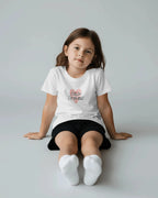 Young girl wearing a white t-shirt with 'Little Princess' text on a plain background