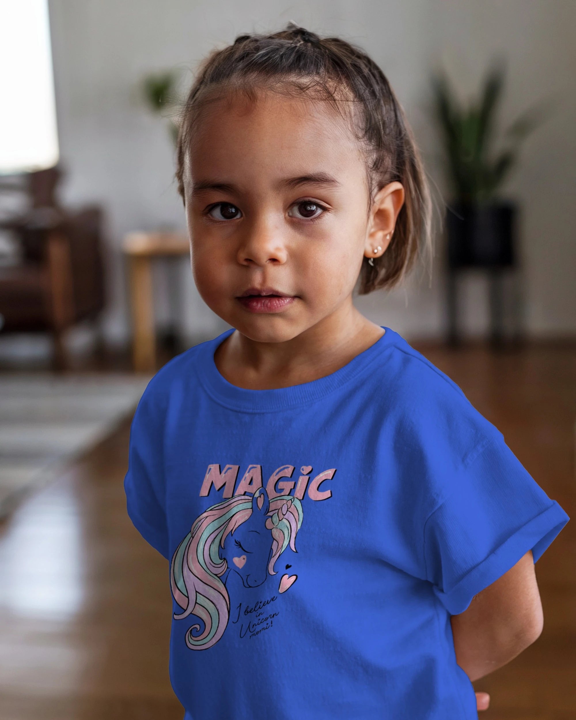 Child wearing a blue t-shirt with a graphic design and text indoors.