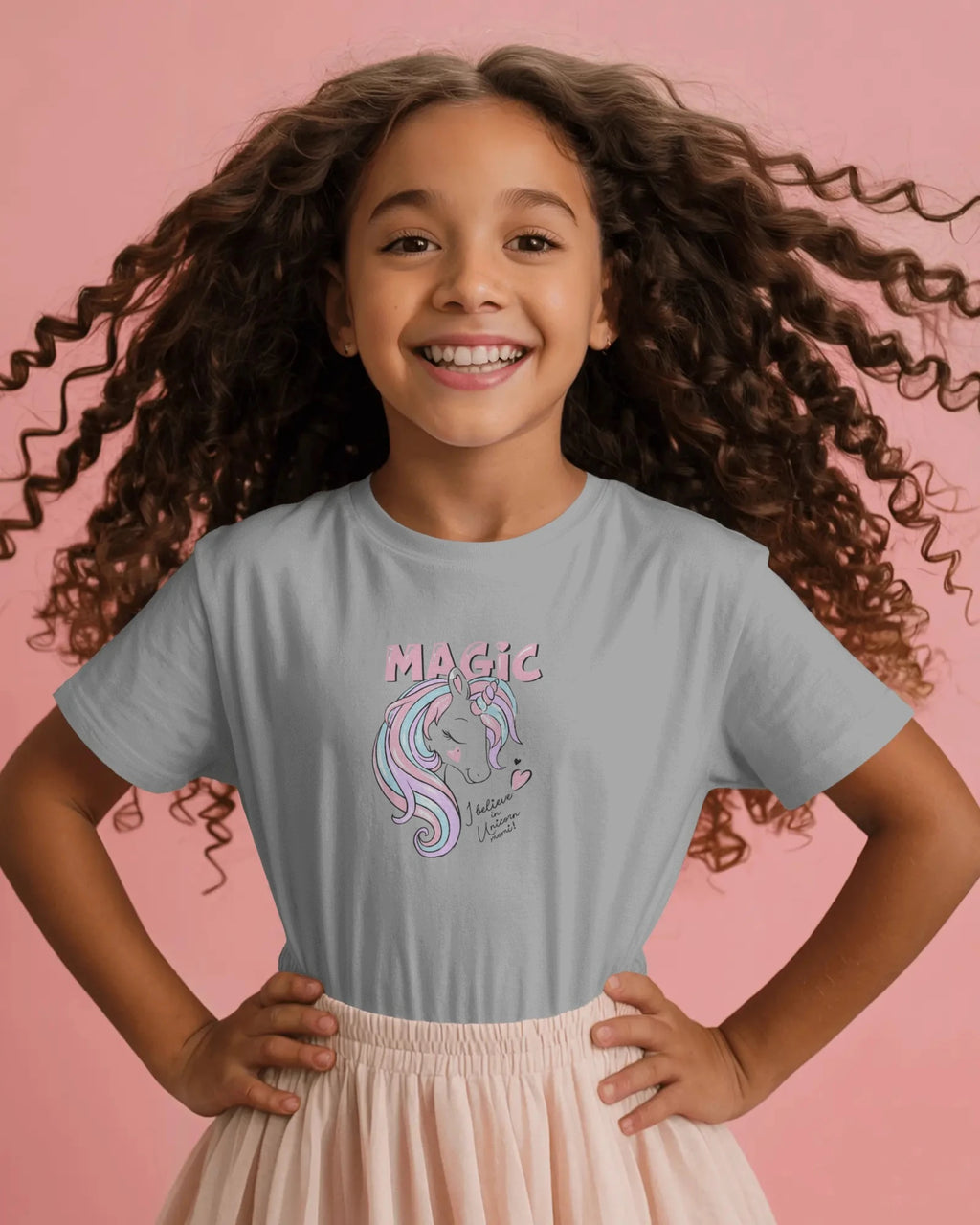 Young girl wearing a gray t-shirt with a unicorn graphic and 'Magic' text on a pink background
