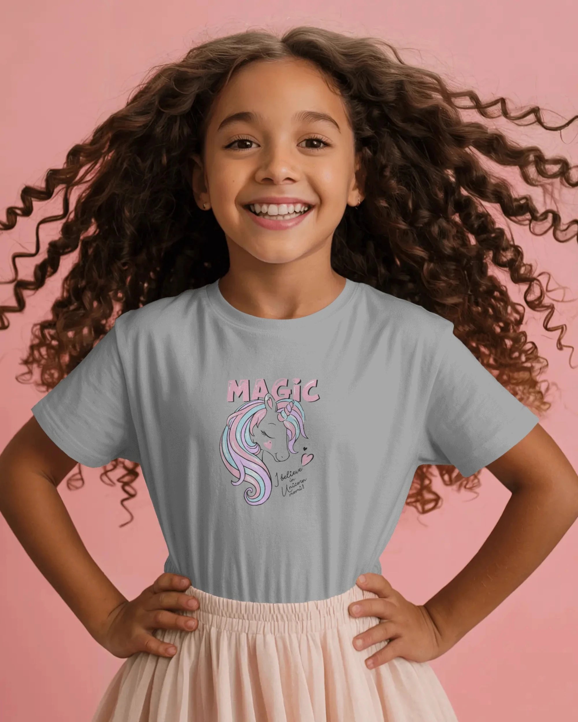 Young girl wearing a gray t-shirt with a unicorn graphic and 'Magic' text on a pink background