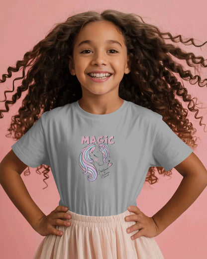 Young girl wearing a gray t-shirt with a unicorn graphic and 'Magic' text on a pink background