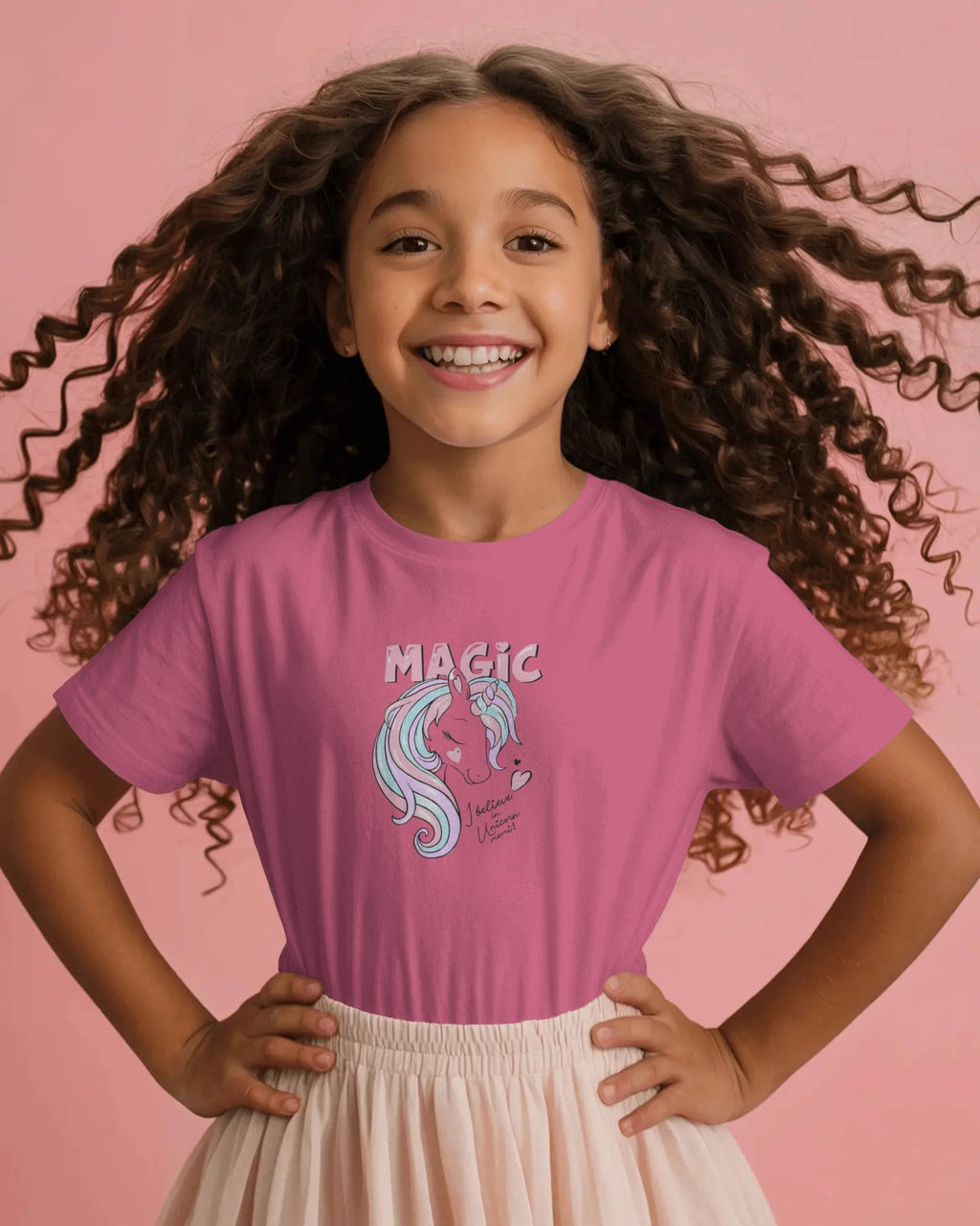 Young girl wearing a pink t-shirt with a unicorn graphic and 'MAGIC' text on a pink background