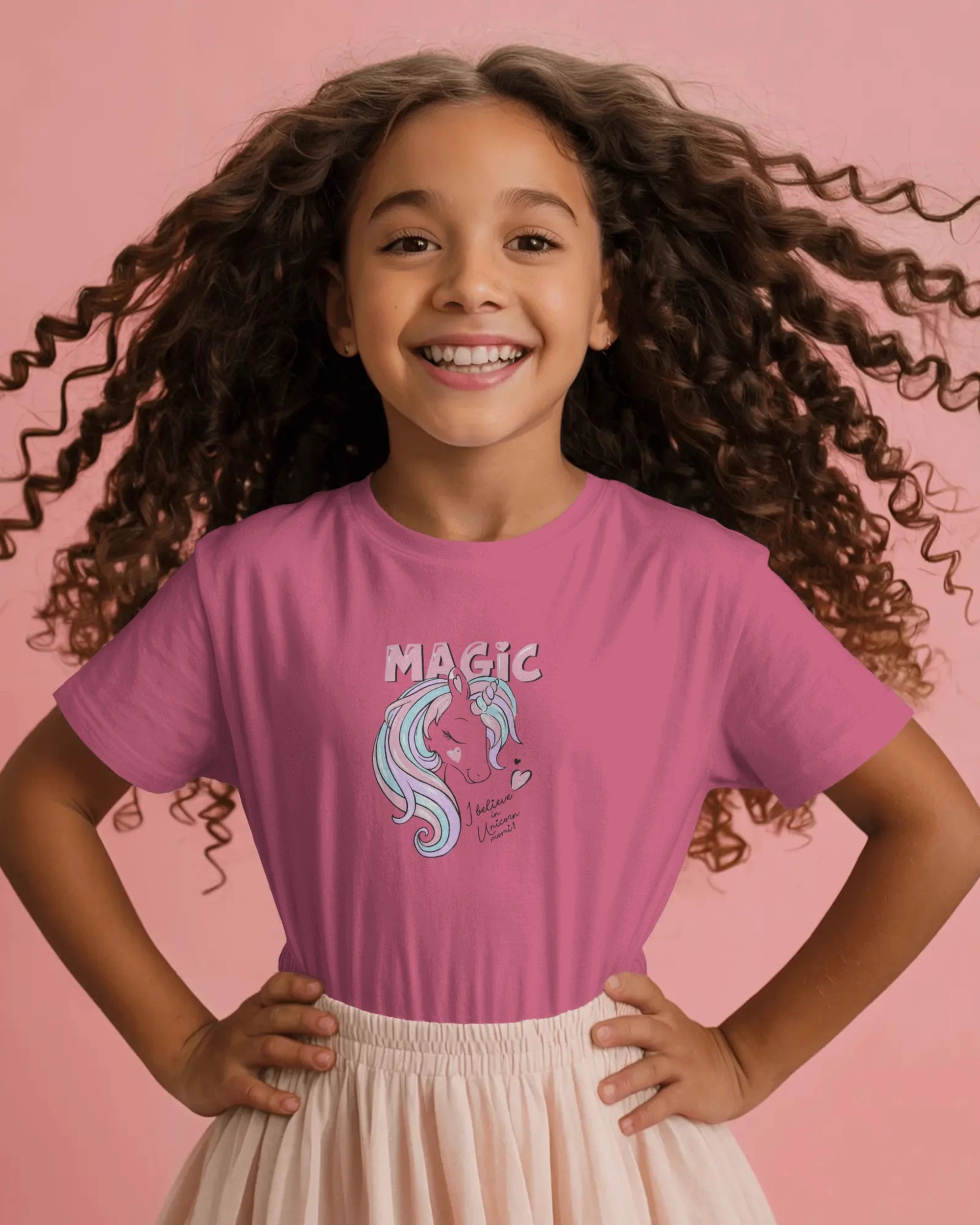 Young girl wearing a pink t-shirt with a unicorn graphic and 'MAGIC' text on a pink background