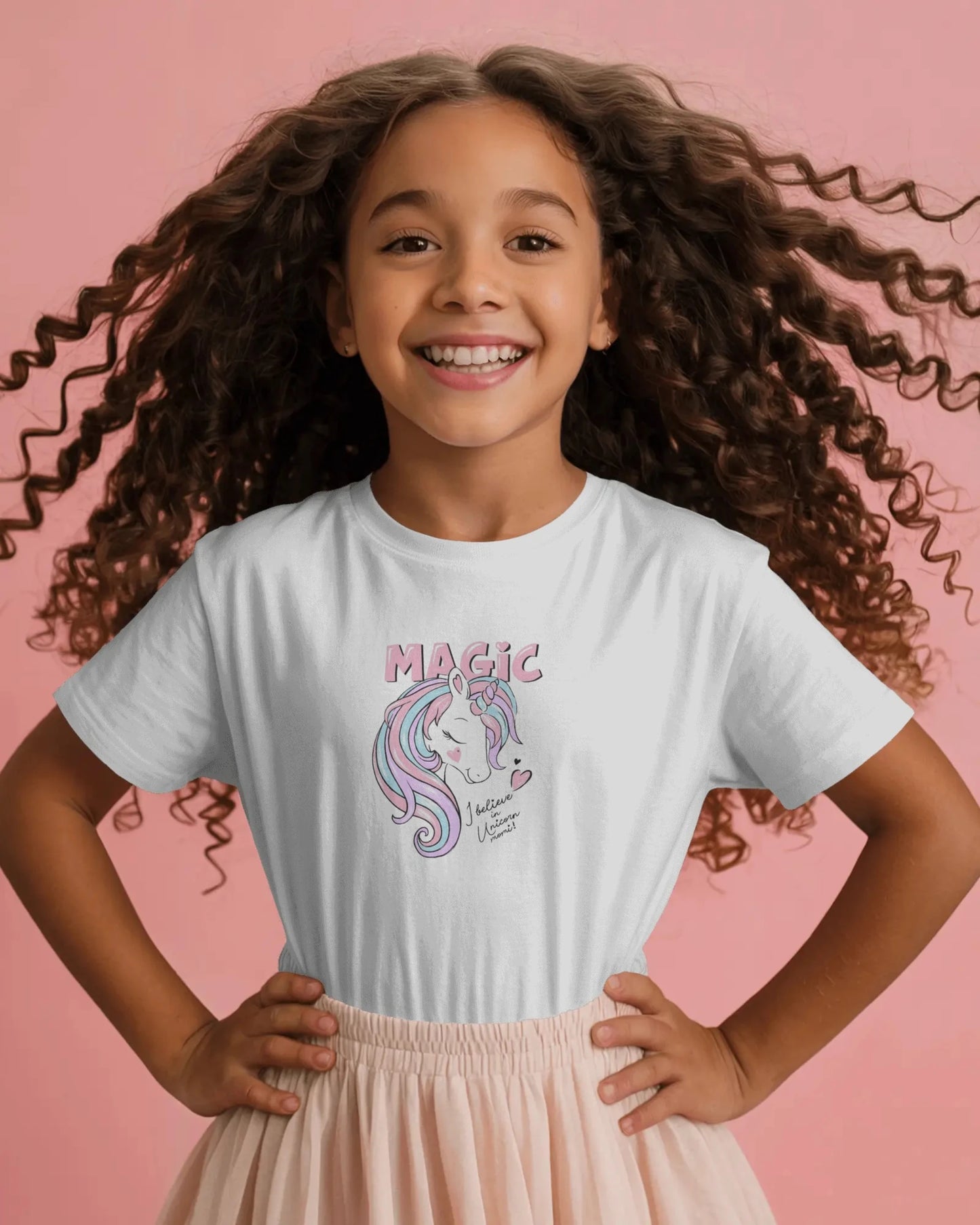 Young girl wearing a t-shirt with a unicorn design and 'Magic' text on a pink background