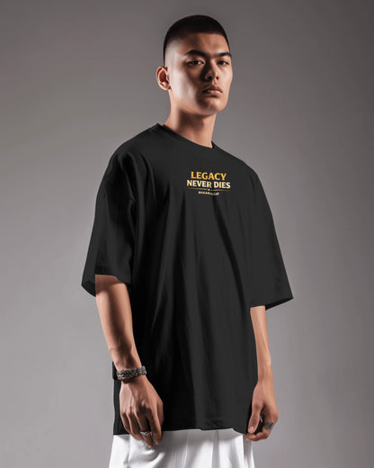 Person wearing a black t-shirt with 'Legacy Never Dies' text on a gray background