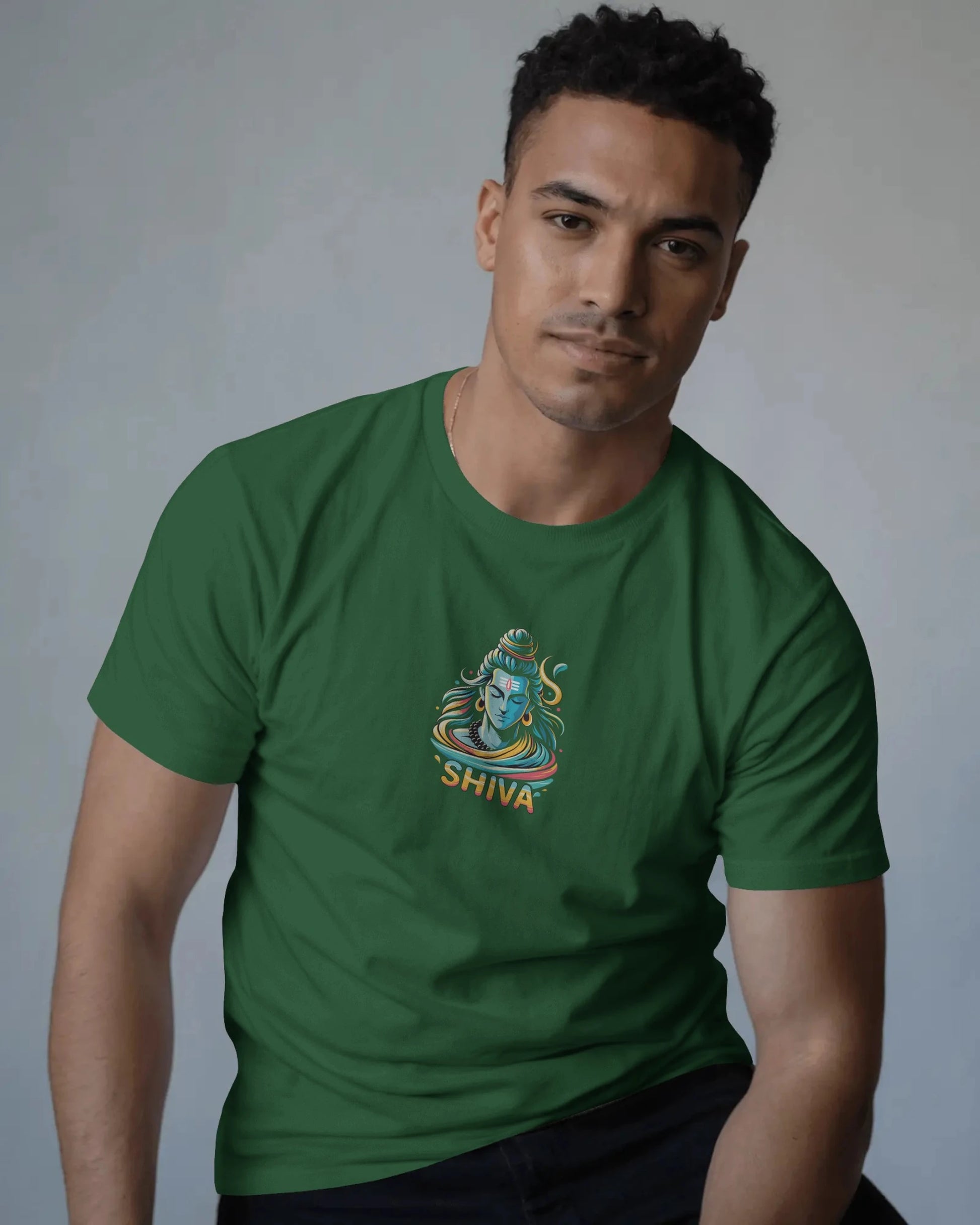 Man wearing a bottel green t-shirt with a Shiva illustration on a gray background