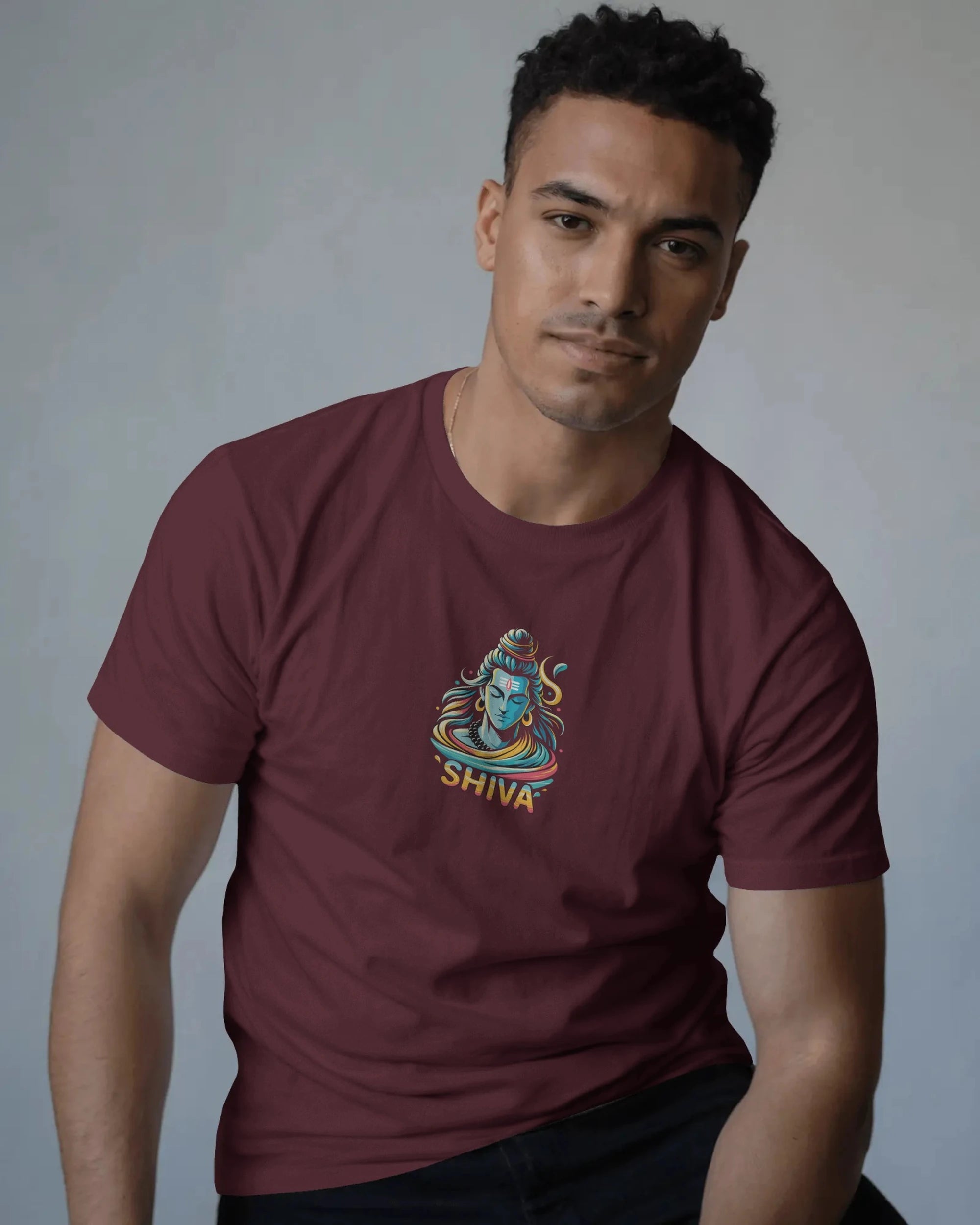 Man wearing a maroon t-shirt with a 'Shiva' design on a gray background