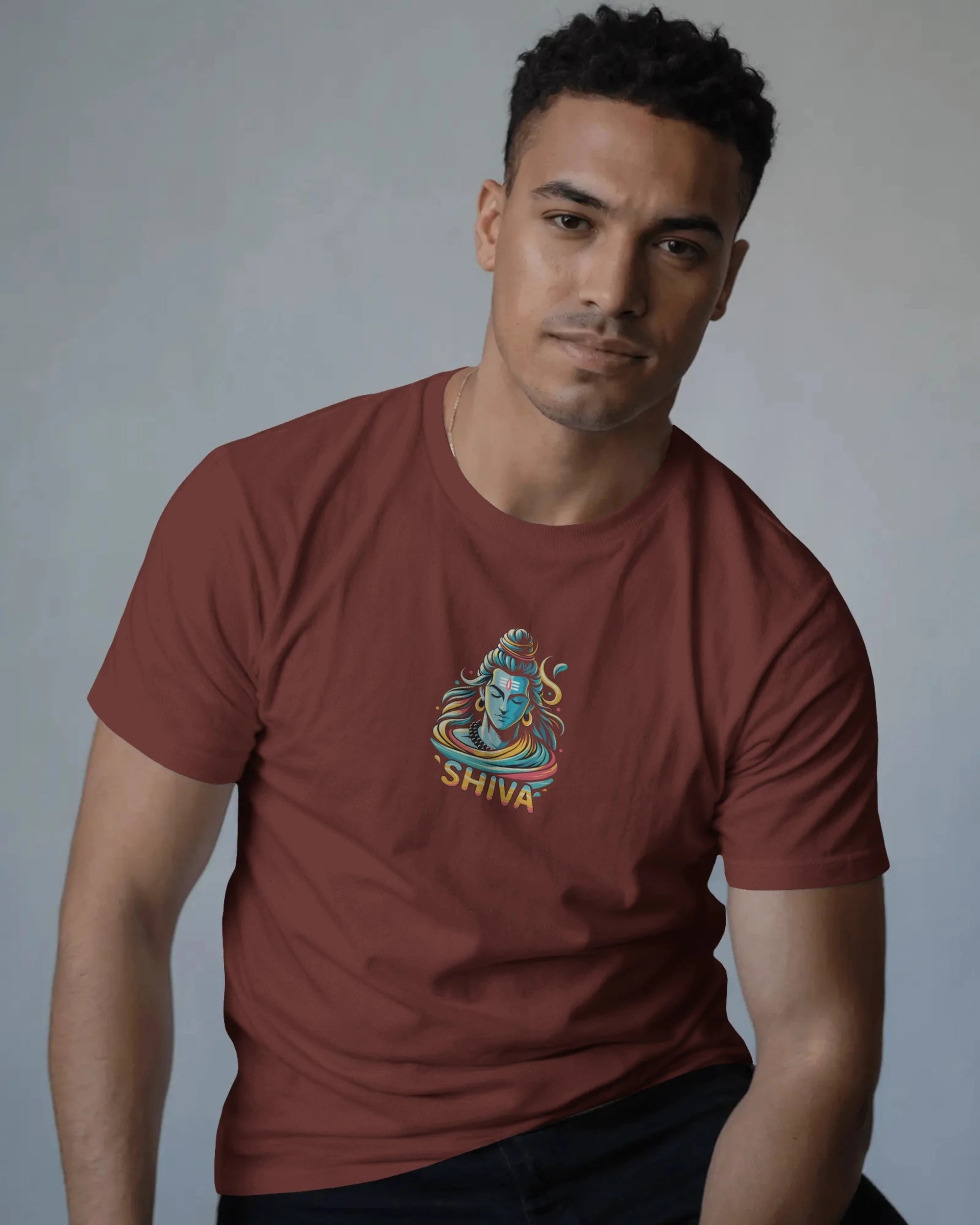 Man wearing a brick red t-shirt with a 'Shiva' design on a gray background