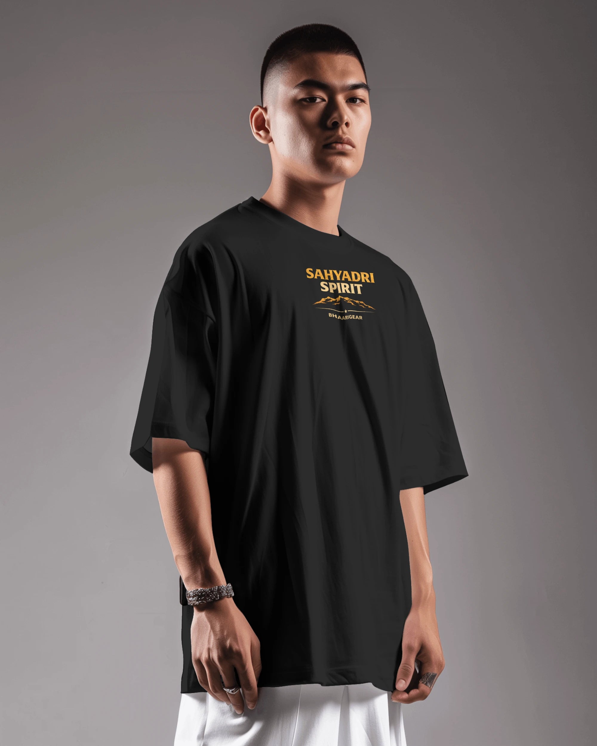 Asian male model wearing Sahyadri Spirit Warrior oversized T-shirt by BhaariGear, showcasing casual streetwear style.