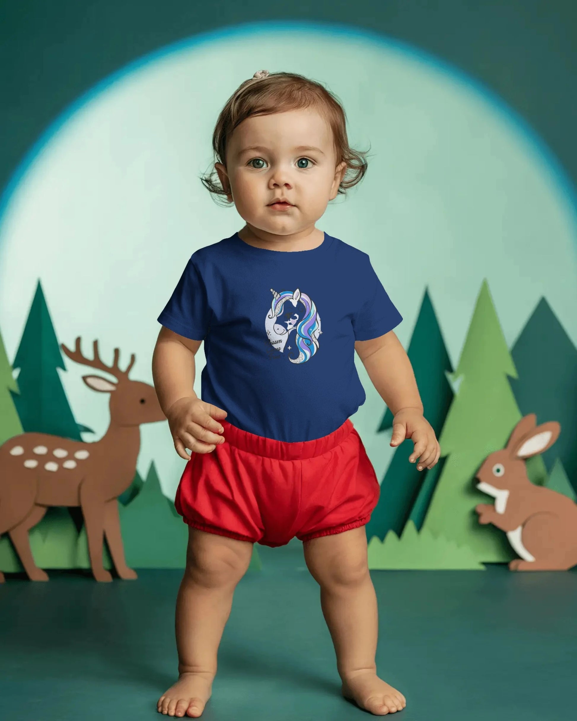 Child wearing a blue shirt with a graphic and red shorts against a forest background