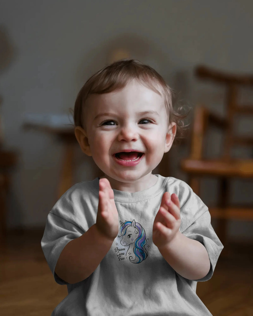 Child clapping hands with a unicorn design on a shirt in a home setting