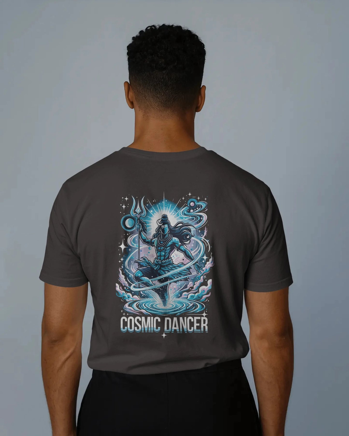 Person wearing a dark coffe brown t-shirt with 'Cosmic Dancer' design on the back against a plain background