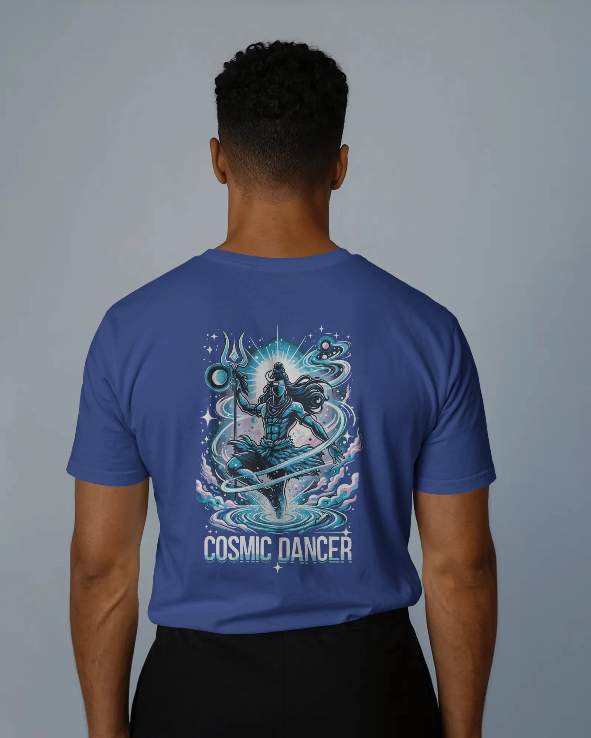 Person wearing a royal blue t-shirt with 'Cosmic Dancer' design on the back against a gray background