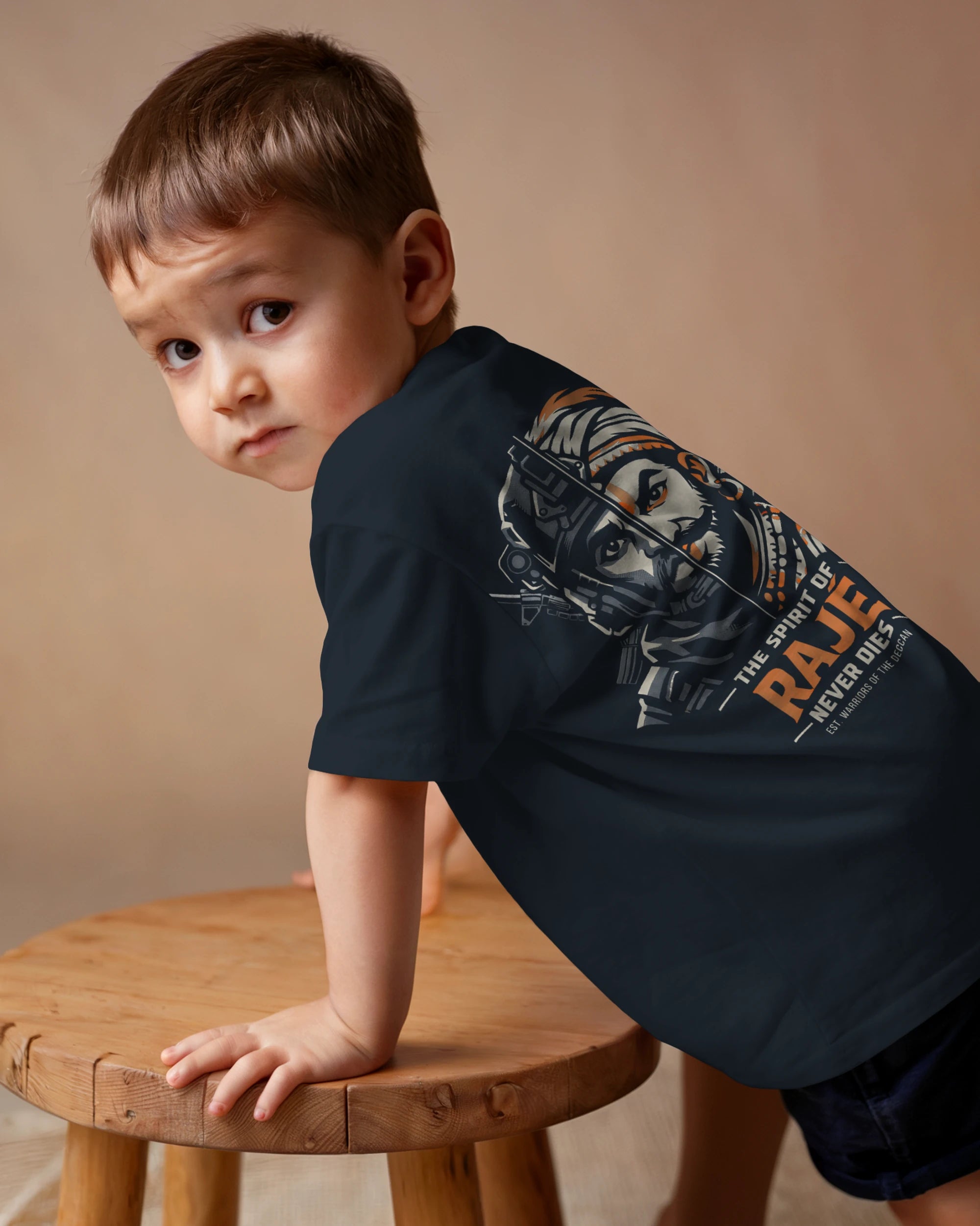 Navy blue Spirit of Raje kids' T-shirt by BhaariGear featuring a warrior legacy design, back view on a simple casual shirt.