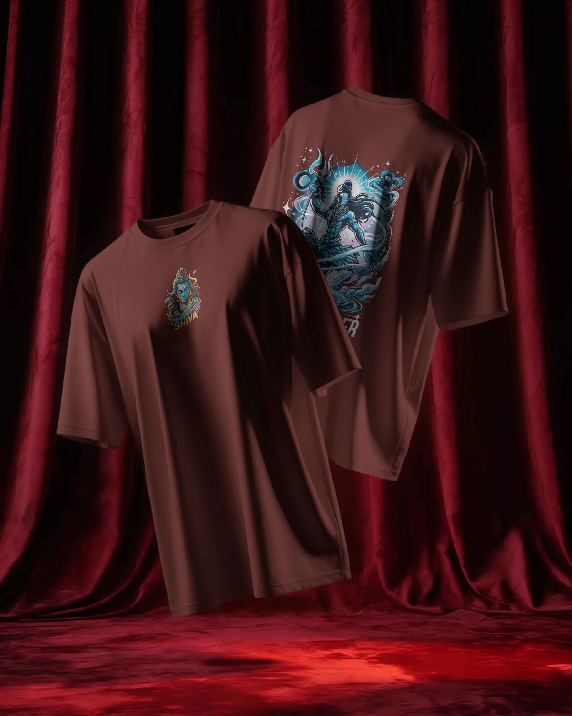 Two brick red t-shirts with graphic designs on a red curtain background