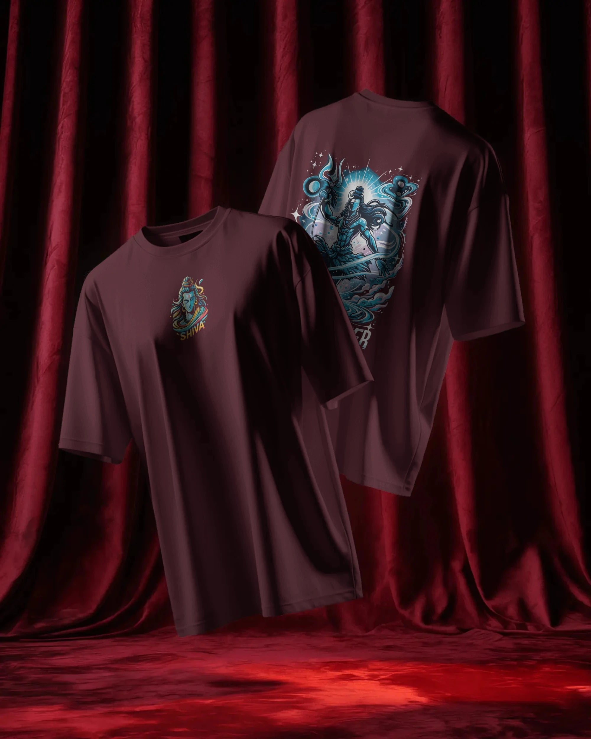 Two maroon t-shirts with graphic designs on a red curtain background