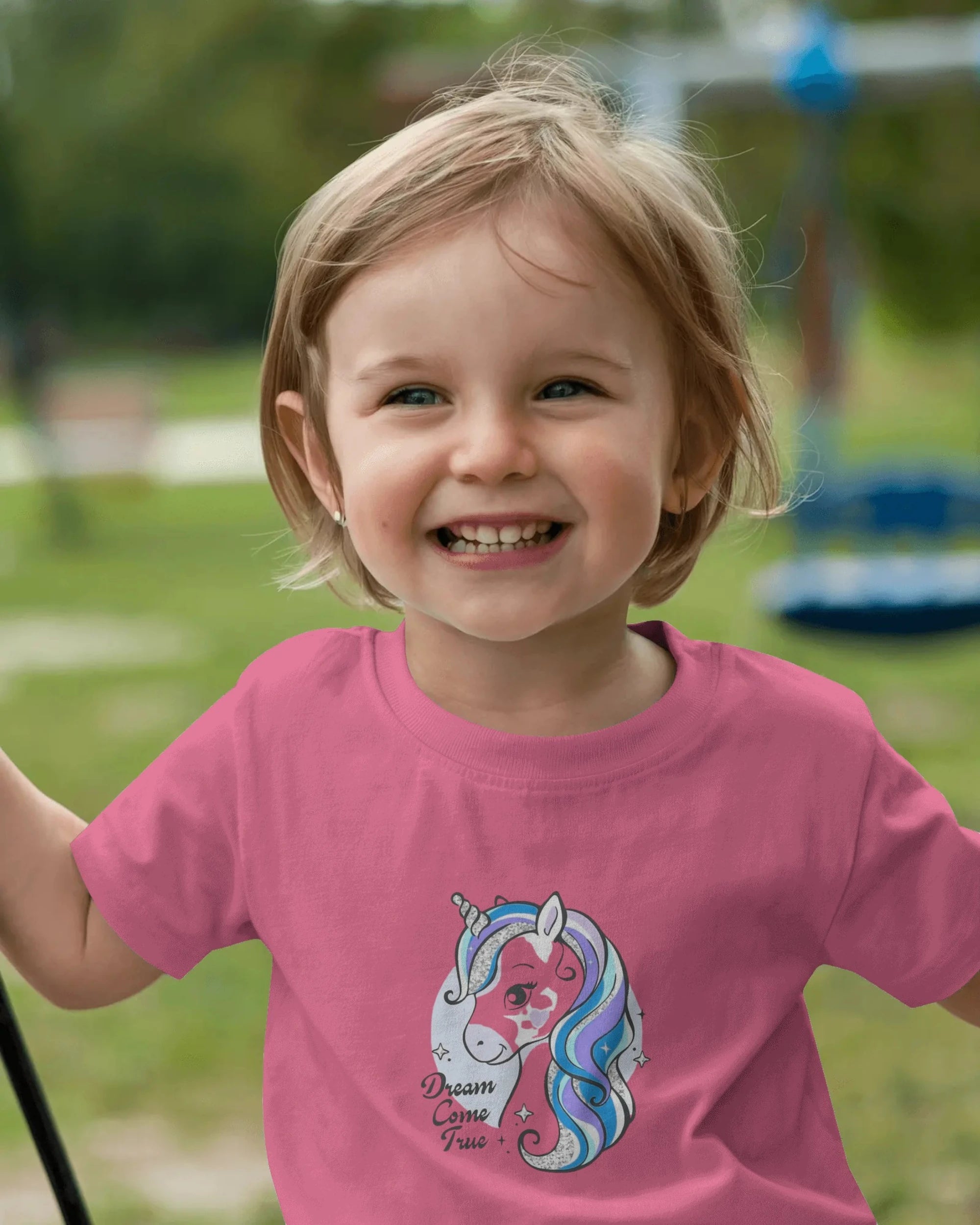 Child wearing a pink t-shirt with a unicorn design outdoors