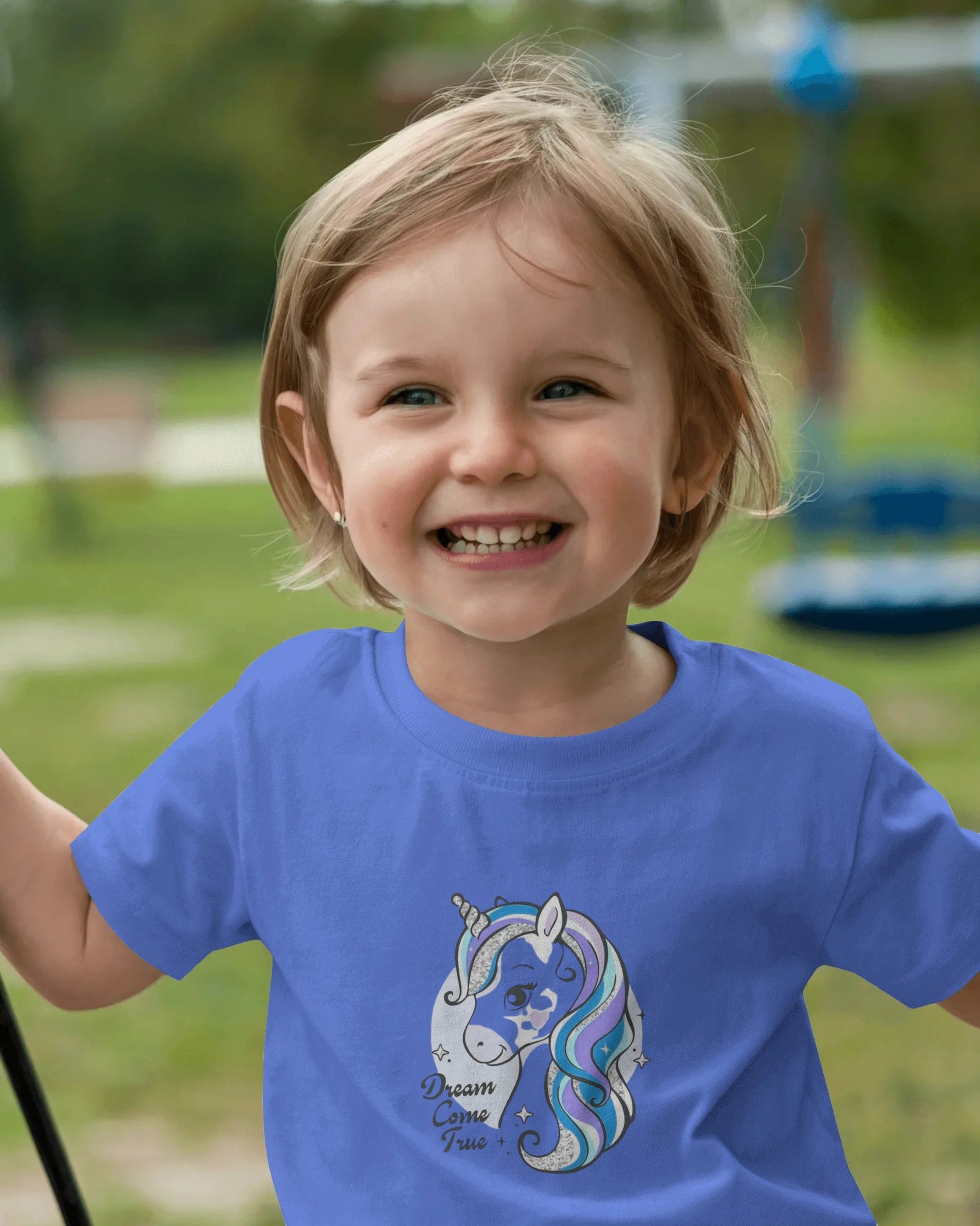 Child wearing a blue t-shirt with a unicorn design outdoors