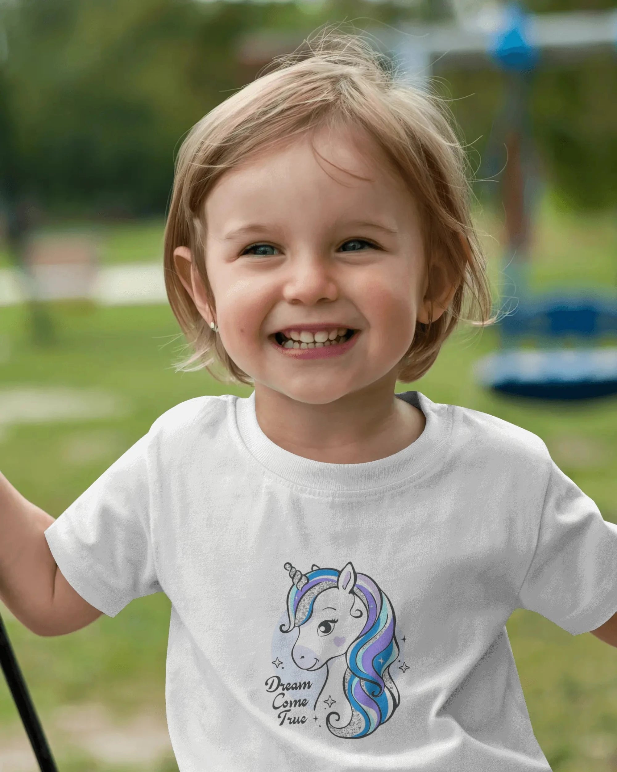 Child wearing a white t-shirt with a unicorn design outdoors