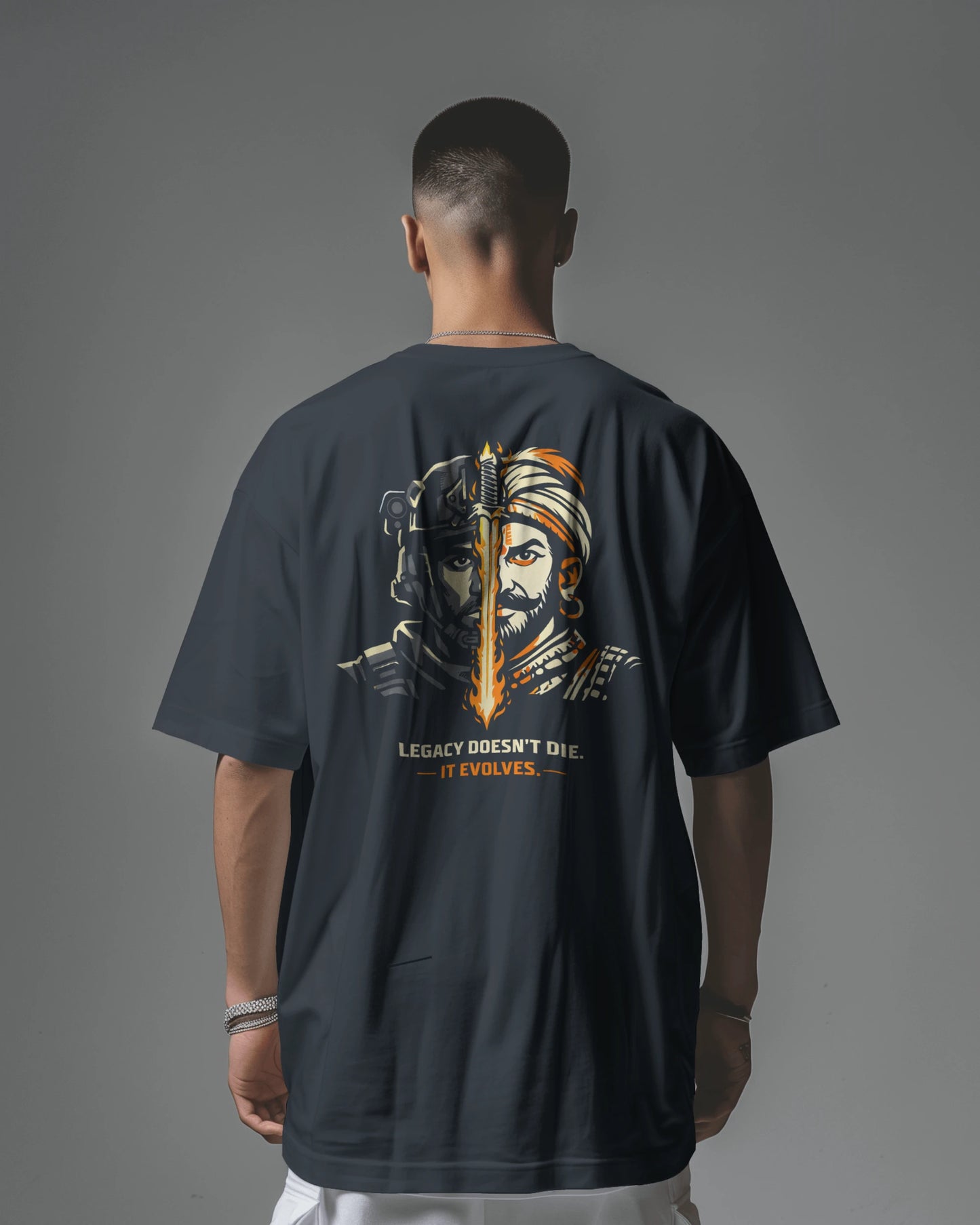 Person wearing a dark navy blue t-shirt with a graphic design on the back against a gray background
