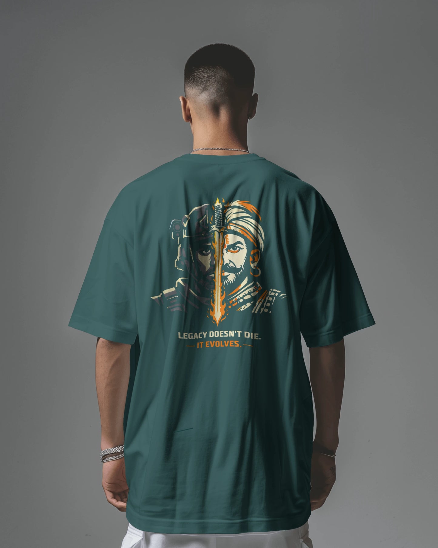 Person wearing a petrol blue  t-shirt with a graphic design on the back against a gray background