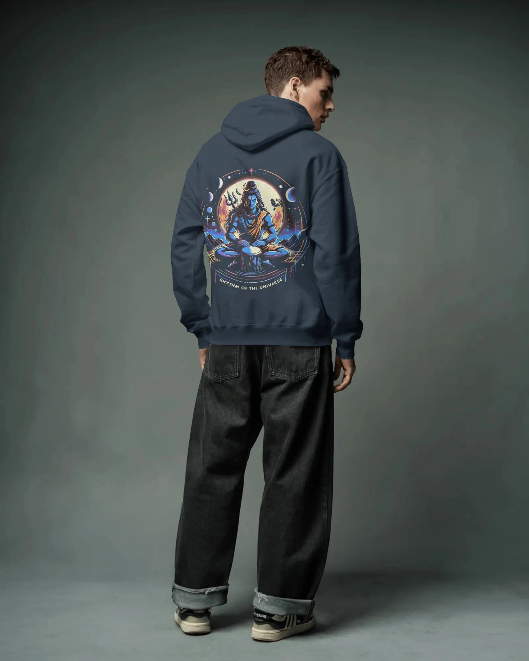 Person wearing a navy blue pull over  hoodie with a colorful graphic on the back against a gray background
