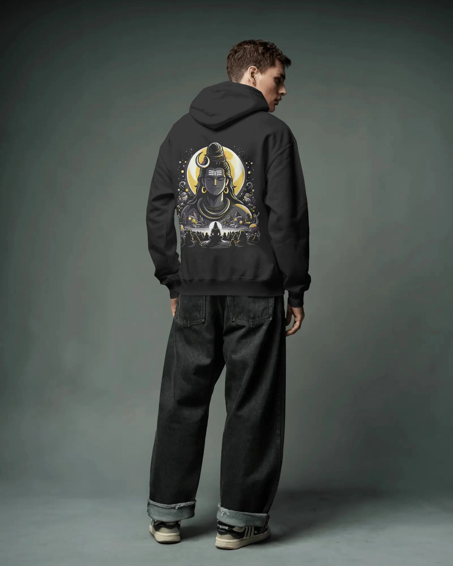 Person wearing a black pull over hoodie with a graphic design on the back against a gray background