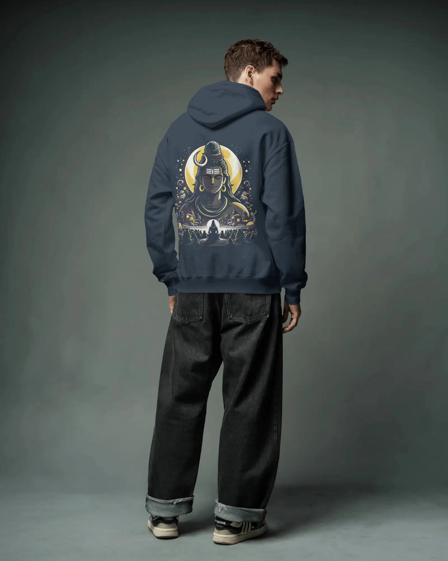 Person wearing a navy blue pull over hoodie with a graphic design on the back against a gray background