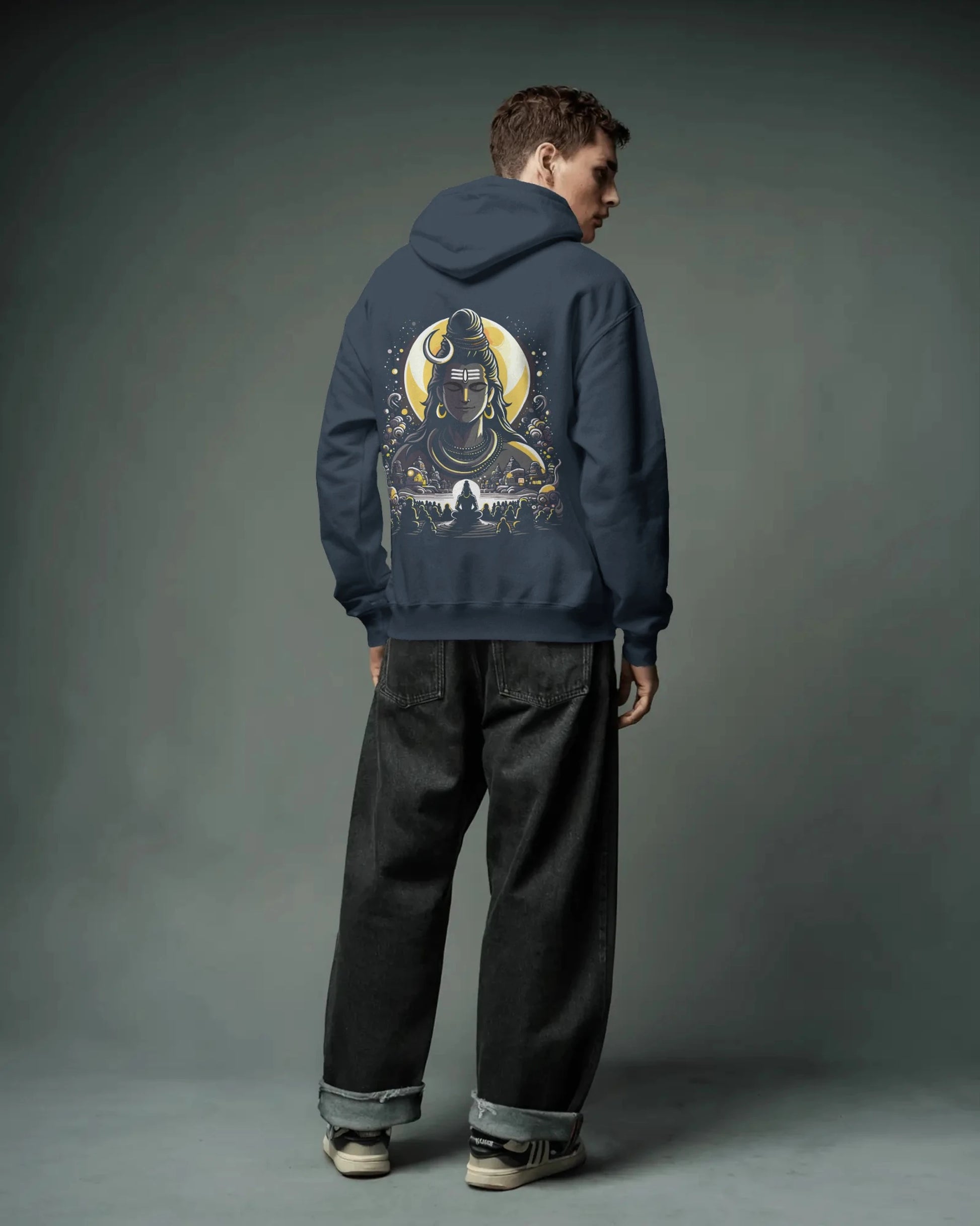 Person wearing a navy blue pull over hoodie with a graphic design on the back against a gray background