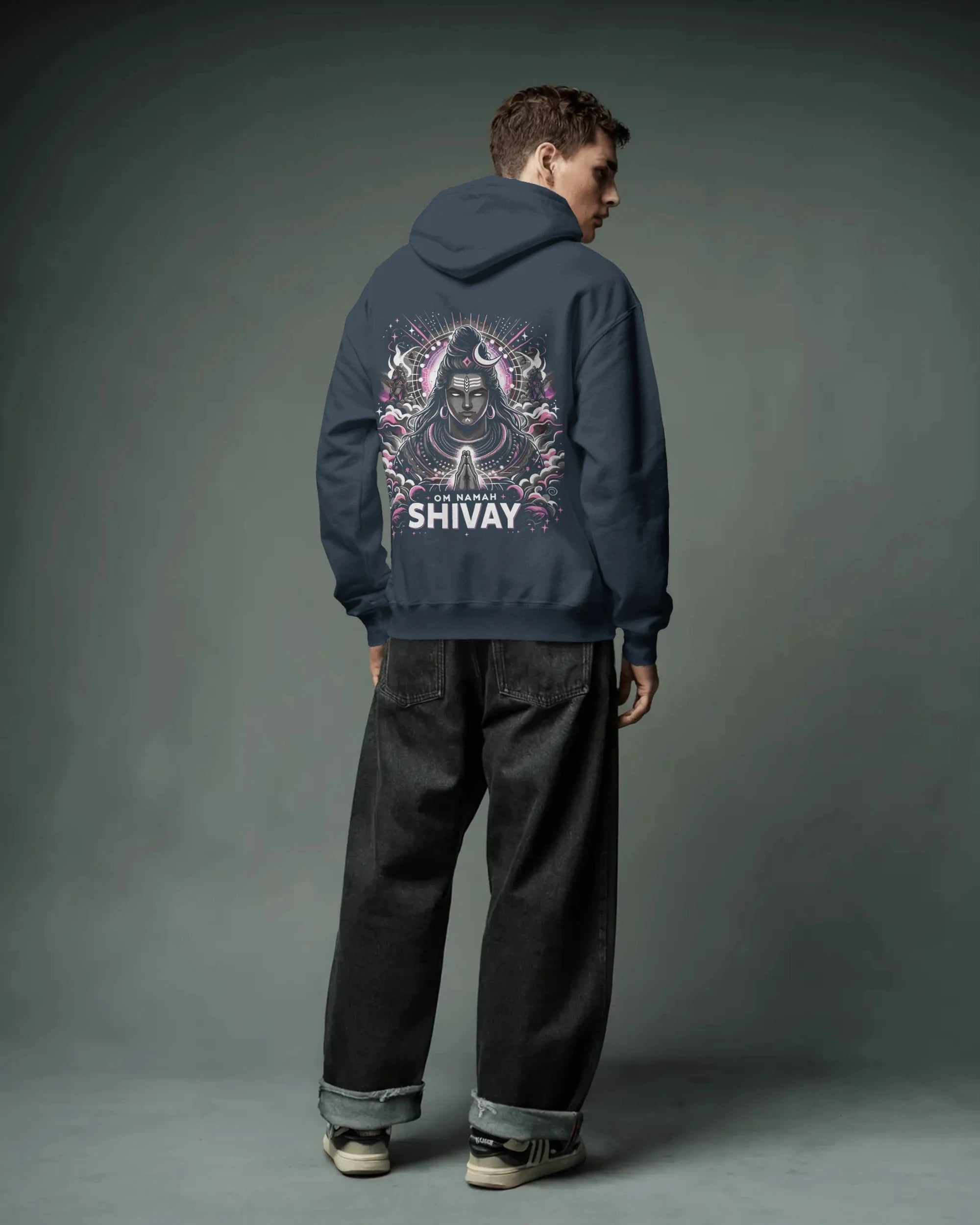 Person wearing a navy blue pulloverhoodie with 'SHIVAY' design on the back against a gray background