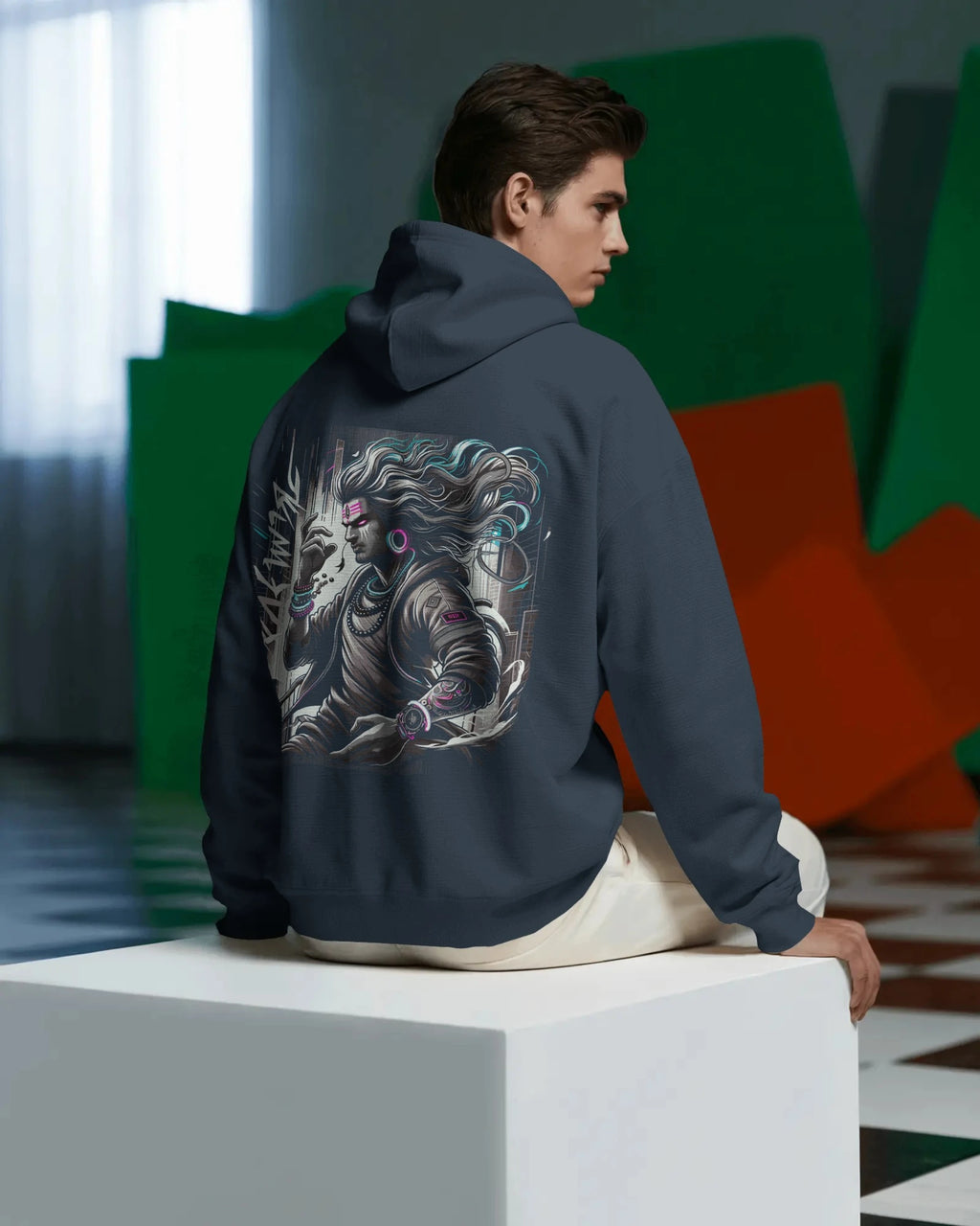 Person wearing a Pullover hoodie with a dragon design on the back, sitting on a white block in a modern indoor setting.
